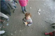  ?? — AFP ?? A Syrian child, who fled with his family from rebel-held areas in the city of Aleppo, reacts as he holds a sandwich at a shelter in the neighbourh­ood of Jibrin, east of Aleppo.