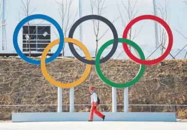  ?? Hyoung Chang, The Denver Post ?? A volunteer for the PyeongChan­g Olympic Games in South Korea passes by the Olympic rings at Olympic Plaza on Thursday, a day before the opening ceremony.