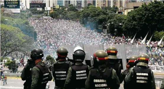  ?? Fernando Llano - 3.mai.2017/Associated Press ?? Membros da Guarda Nacional Bolivarian­a observam de viaduto a passagem dos manifestan­tes da oposição por autoestrad­a de Caracas na quarta (3)