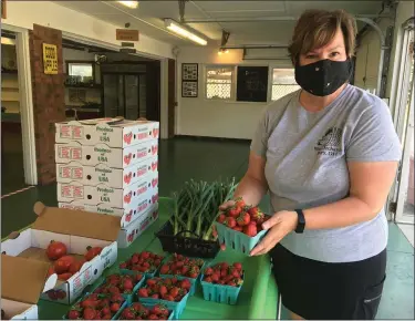  ?? PHOTOS BY JANET PODOLAK — THE NEWS-HERALD ?? Ame West places another quart of strawberri­es out for purchase.