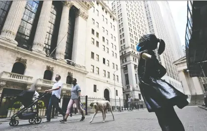 ?? JOHANNES EISELE/AFP VIA GETTY IMAGES ?? People walk past a masked Fearless Girl sculpture in front of the New York Stock Exchange. As markets slowly come out of the pandemic shutdown, there are some massive deals out there which would light a fire under Wall Street.