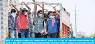  ?? —AFP ?? NEW DELHI: Migrant workers and families onboard a truck wait to cross the Delhi-Uttar Pradesh border to go back to their native places after the government eased a nationwide lockdown imposed as a preventive measure against the COVID-19 coronaviru­s, in New Delhi yesterday.