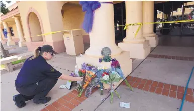  ?? ADOLPHE PIERRE-LOUIS/JOURNAL ?? Danielle Bell, a security guard at Clovis High School, puts flowers at a memorial for the victims of Monday’s mass shooting at the Clovis-Carver Public Library.