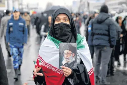  ?? EBRAHIM NOROOZI AP ?? An Iranian woman holds up a portrait of Iranian Supreme Leader Ayatollah Ali Khamenei, as she makes the victory sign during a rally marking the 40th anniversar­y of the 1979 Islamic Revolution, in Tehran, Iran, on Monday. •