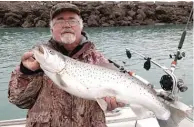  ?? DALE BOWMAN/ FOR THE SUN- TIMES ?? TOP: The fishing ambience from the Indiana shoreline of Lake Michigan. ABOVE LEFT: Dale Bowman with a big brown trout caught April 21 off Gary Light. ABOVE RIGHT: The smoked version of the catch, gussied up with fresh sprigs of homegrown parsley.