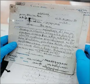  ?? (File Photo/AP/Sakchai Lalit) ?? Retired Thai Air Chief Marshal Sakpinit Promthep looks at a World War II-era local Thai police report April 29 in the archive room of the Thai Air Force Museum in Bangkok.