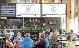  ?? BRADEN FASTIER/ STUFF ?? An advertisin­g billboard displays a government health message about the Covid-19 situation as cafe patrons take a break at Nelson Airport.