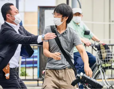  ?? Associated Press ?? ■ Tetsuya Yamagami, center, holding a weapon, is detained Friday near the site of gunshots in Nara, western Japan. The 16-inch firearm used to kill former Prime Minister Shinzo Abe on Friday as he campaigned for his ruling party in Nara, western Japan, looked crude, more like a propellant made of pipes taped together and filled with explosives.