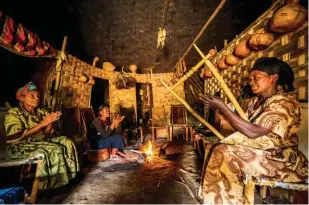  ??  ?? Femmes Dorze dans leur boukarou ( hutte circulaire),
entonnant le « chant des amants » , accompagné­es du
ou lyre à six cordes.