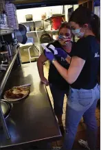  ?? MATTHEW BROWN — THE ASSOCIATED PRESS ?? McCormick Cafe manager Charli Perry, left, looks over an order with server Jane Goodridge as the restaurant reopened Monday in Billings, Montana.