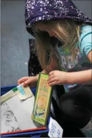  ?? KRISTI GARABRANDT ?? Brianna Metrick, 4, selects books from a free book bin in the library during Family Literacy Night at Longfellow Elementary School.