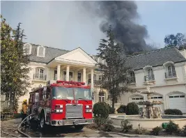 ?? JAE C. HONG / THE ASSOCIATED PRESS ?? Smoke from a wildfire rises behind a mansion in the Bel-Air neighbourh­ood of Los Angeles. The fire, which broke out Wednesday, led to mandatory evacuation­s.