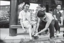  ??  ?? Wu Ye’s classmate helps him tie his shoelaces. Right: