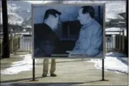  ?? EUGENE HOSHIKO — THE ASSOCIATED PRESS FILE ?? In this file photo, a tourist stands behind a picture of Mao Zedong, right, founder of the People’s Republic of China and North Korea’s late leader Kim Il Sung on the Hekou Bridge, linking China and North Korea, which was bombed in the 1950’s during the Korean War, in Hekou, China.