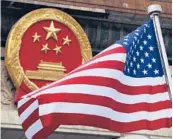  ?? ANDY WONG/AP 2017 ?? An American flag is flown next to the Chinese national emblem. Beijing is said to be trying to develop the world’s largest bio-database.