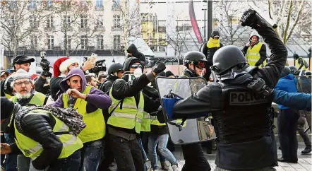  ?? — AFP ?? Pushed back: Riot police clashing with men in yellow vests near the Arc de Triomphe in Paris .