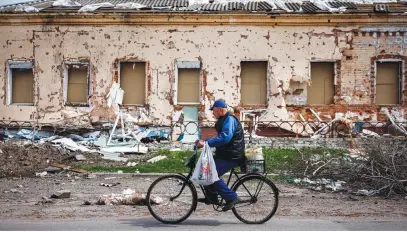  ?? Picture: AFP ?? SIGN OF THE TIMES. A man rides a bicycle past a destroyed house in the village of Derhachi north of Kharkiv, eastern Ukraine, on Wednesday.