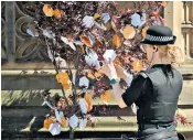  ??  ?? A police officer, left, looks at messages hung from a ‘tree of hope’; a woman comforts two young children during the minute’s silence in St Ann’s Square, right; bees painted on stones, below, left in tribute to all the victims of the terror attack