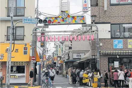  ??  ?? At the west entrance to the Sunamachi Ginza shopping street in Tokyo’s Koto Ward, customers line up in front of a famous fish seller.