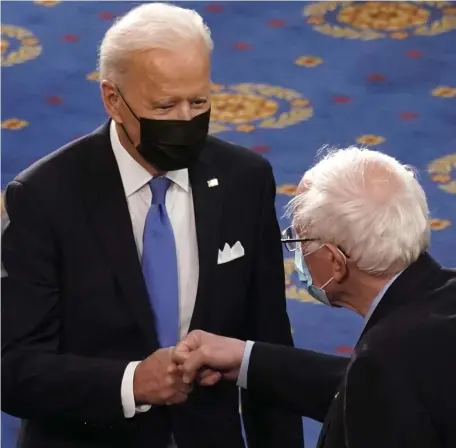  ?? AP FILe ?? FOLLOWING, NOT LEADING: President Biden fist bumps Vermont U.S. Sen. Bernie Sanders, right, before his address to a joint session of Congress in the House Chamber on April 28 in Washington, D.C. The president has adopted many far-left ideas from liberal darlings like Sanders, Bay State U.S. Sen. Elizabeth Warren and New York U.S. Rep. Alexandria Ocasio-Cortez.