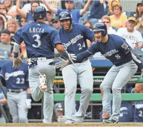  ?? GETTY IMAGES ?? Orlando Arcia is greeted at home plate by Ryan Braun (8) and Jesus Aguilar after coming around to score on a wild pitch in the sixth inning.