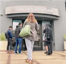  ?? Jeff Chiu/Associated Press ?? People stand outside a closed Silicon Valley Bank branch in Santa Clara, Calif., after it shut down this spring.