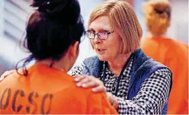  ?? [PHOTOS BY PAUL HELLSTERN, THE OKLAHOMAN] ?? Jail chaplain Sally Riesenberg talks with an inmate as she and other volunteers distribute cookies, handmade Christmas cards and bottles of shampoo Wednesday at the Oklahoma County jail.