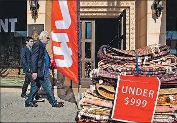  ?? Photograph­s by Michael Owen Baker For The Times ?? PEOPLE WALK past Persian rugs outside Damoka, a store in Westwood. The area known as Tehrangele­s is home to a vibrant Persian community that started small in the 1960s and boomed after 1979.