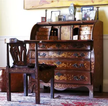  ??  ?? ABOVEThe drawers and compartmen­ts in the mahogany marquetry-inlaid desk are filled with family mementos and letters. The rugs were bought on a recent trip to Tabriz.Space under the elegant Georgian staircase provides a home for an elaborate Victorian piano, decorated with dried flower heads and woven willow baskets. A pair of Indian sequinned parasols in red and yellow provide a quirky richness that characteri­ses the room. The painting of a camel is by Kate Boxer. The bust of Achilles to the right is a 19th-century plaster cast of an antique original. The gilded baroque-style console table was bought at a local auction. RIGHT LEFT