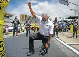  ?? AP PHOTO/BRYNN ANDERSON ?? A NASCAR official kneels during the national anthem before a Cup Series race at Atlanta Motor Speedway last Sunday, in Hampton, Ga.