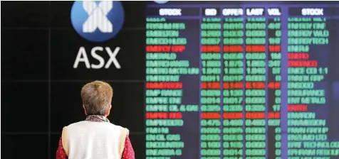  ?? — Reuters ?? An investor looks at a board displaying stock prices at the Australian Securities Exchange (ASX) in Sydney, Australia on Friday.