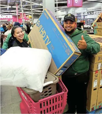  ?? Picture: THEO JEPTHA ?? GOOD SERVICE: Chesrin Davids(left) from Game helps Ross Cooper with his new tv that he bought just after the doors open at Game in Vincent Park, East london.