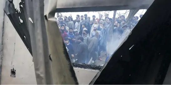  ?? Picture: AFP ?? Kashmiri Muslims onlookers gather near a damaged house after a gunfight between militants and Indian government forces at Mujgund area on the outskirts of Srinagar yesterday.