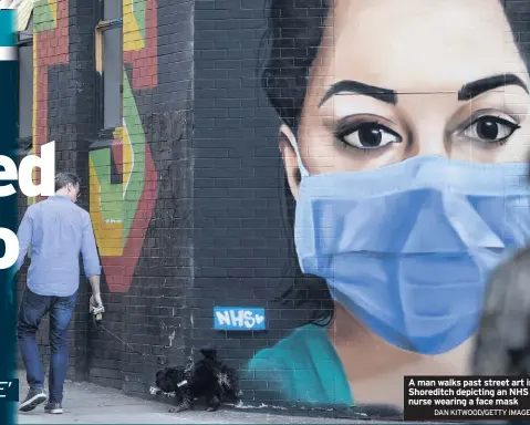  ?? DAN KITWOOD/GETTY IMAGES ?? A man walks past street art in Shoreditch depicting an NHS nurse wearing a face mask