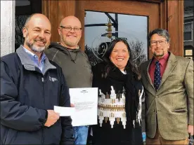  ??  ?? Miamisburg Community Foundation Vice President Shon Myers (left) and foundation President Greg Bell (right) present a check to A Taste of Wine owners Chris and Urmila Holloway on Friday, Jan. 8. The check was one of three distribute­d to area eateries by the foundation’s newly establishe­d Louis Epperson Restaurant Rescue Fund.
