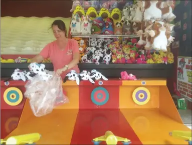  ?? DAVID S. GLASIER — THE NEWS-HERALD ?? Amy Otterbache­r of Seville unpacks prizes at the Firehouse Water race amusement stand on the Cuyahoga County Fairground­s.