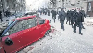  ?? AFP ?? Croatian Prime Minister Andrej Plenkovic, centre, and Croatian Health Minister Vili Beros walk past destroyed building and cars in downtown Zagreb yesterday to look at the damage after an earthquake hit the country.