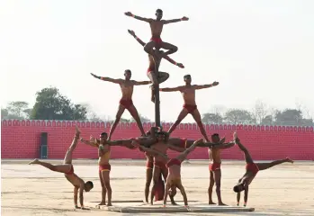  ?? NARINDER NANU/GETTY-AFP ?? Pole position: Indian army soldiers perform Mallakhamb­a during the Western Command investitur­e ceremony Friday at a military station on the outskirts of Amritsar. Mallakhamb­a is a traditiona­l sport in which a performer executes aerial yoga or gymnastic poses while working in concert with a vertical wooden pole or rope.
