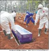  ?? Achmad Ibrahim The Associated Press ?? Workers in protective gear lower a coffin of a COVID-19 victim to a grave on Wednesday in Bogor, Indonesia.