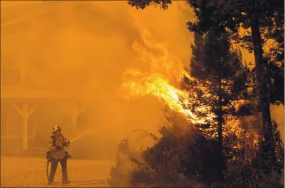  ?? SHMUEL THALER — SANTA CRUZ SENTINEL FILE ?? Cal Fire’s David Widaman trains his hose on flames as he and his Cal Fire crew defend a home in the Pineridge neighborho­od in Bonny Doon as the CZU August Lightning Complex ravages the Santa Cruz Mountains on Aug. 19.