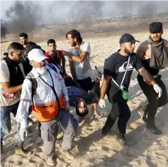  ??  ?? Palestinia­n demonstrat­ors and paramedics carry a wounded man on a stretcher during a protest calling for an end to the Israeli blockade on Gaza, on a beach in Beit Lahia near the maritime border with Israel. — AFP photo