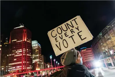  ?? AP Photo/David Goldman, File ?? In this Nov. 4 file photo, Betsy Camardo, who supports Joe Biden, holds a sign outside the central counting board where ballots in the general election are counted in the city at the TCF Center in Detroit. President Donald Trump and his allies have made many accusation­s of a “rigged election” for months, sharing accusation­s through various media and even lawsuits about fraudulent votes and dead voters casting ballots. While the details of these spurious allegation­s may fade over time, the scar it leaves on American democracy could take years to heal.