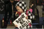  ??  ?? Violet, 1, holds a sign saying “don’t be cruel” on Saturday in Chico.