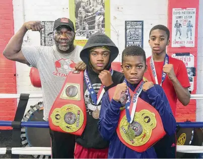  ?? Arnold Gold/Hearst Connecticu­t Media ?? From left, Solomon “Coach Solo” Maye, Troy “Trigga” Moore, 13, Amare “Triple R” Foster, 10, and his brother, Amir “No Fear” Foster, 12, at the Get ‘Em Boy Boxing Gym in New Haven. Moore and the Foster brothers are holding their Junior Olympics medals and belts from the National Silver Gloves tournament.