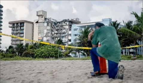  ?? Joe Raedle / Getty Images ?? A man prays near where search and rescue operations continue at the site of the partially collapsed Champlain Towers South condo building on Friday in Surfside, Fla. The man, overcome with emotion, said he had lost a relative in the collapse.