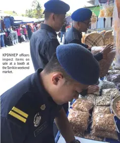  ??  ?? KPDNHEP officers inspect items on sale at a booth at the Serikin weekend market.