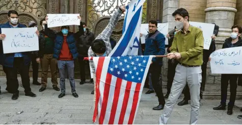  ?? Foto: dpa ?? Demonstran­ten in Teheran verbrennen Fahnen der USA und von Isreal. Sie fordern nach der Ermordung eines Atomphysik­ers eine harte Antwort ihrer Regierung.