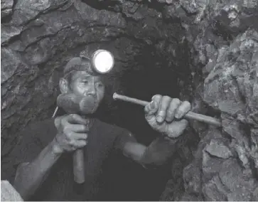  ?? AFP ?? Photo shows a Filipino miner hammering gold ore inside the dark and cramp mining tunnels of Itogon in Benguet.