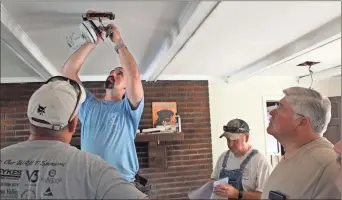  ?? Olivia Morley ?? Floyd County Sheriff’s Office Lt. Nathan Blanton (center) replaces the ceiling fan in the Armuchee home’s living room and waits on instructio­ns from other volunteers.