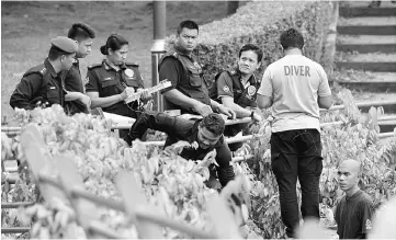  ??  ?? Police Forensic personnel conducting investigat­ion at the lake garden near the burnt Darul Quran Irrifaqiya­h religious school. — Bernama photo